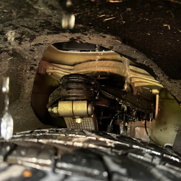 Close-up view of a Tesla Model 3 undercarriage, pointing out a potential safety concern related to the upper control arm failure.